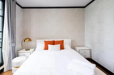 a bedroom with a large white bed with orange pillows at Stylish 7Beds Poolhouse with Cinema Lift - 2min to BTS in Amphoe Phra Khanong