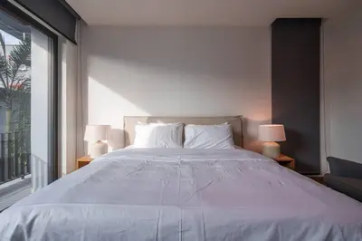 a bedroom with a large bed with two lamps at MonochromeDesignerPool Villa in Bangkok