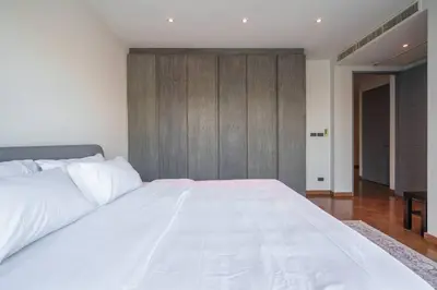 a bedroom with a large white bed with a wooden wall at MonochromeDesignerPool Villa in Bangkok