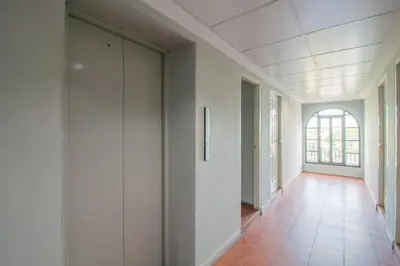 an empty hallway with white walls and a window at Resortel Lat Phrao 91 in Bangkok