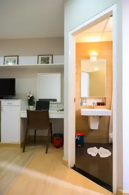 a bathroom with a sink and a desk with a mirror at CU iHouse เรือนวิรัชมิตร in Bang Rak