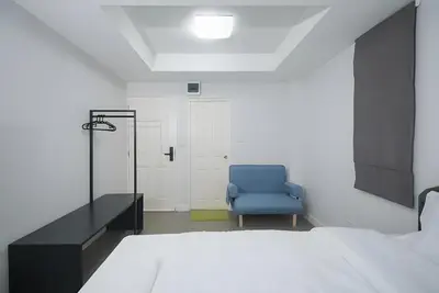 a blue chair in a room with a bed at XX Mitr Inn The Grand Palace Bangkok - Samyot in Bangkok