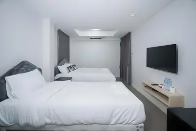 a hotel room with two beds and a flat screen tv at XX Mitr Inn The Grand Palace Bangkok - Samyot in Bangkok