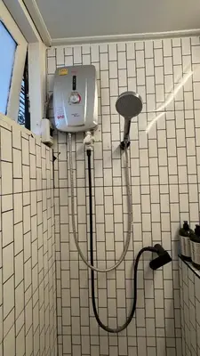 a white tiled bathroom with a blow dryer on the wall at Cozy Cat Souluna home in Ekkamai in Bangkok