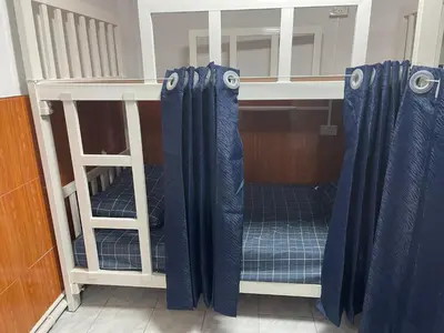 a bunk bed with blue curtains in a room at ESSENCE Home in Bangkok