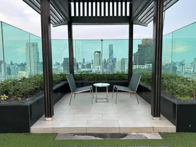 a patio with two chairs and a table on a building at Condo, 3-min walk to BTS, Sky pool, Gym, Wifi, Self check-in at pickup point in Bangkok
