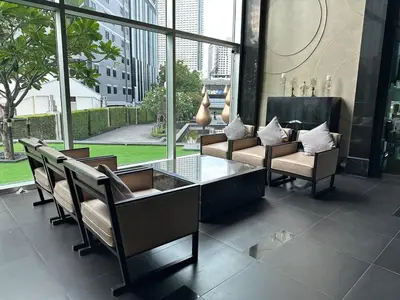 a lobby with chairs and a glass table and windows at Condo, 3-min walk to BTS, Sky pool, Gym, Wifi, Self check-in at pickup point in Bangkok