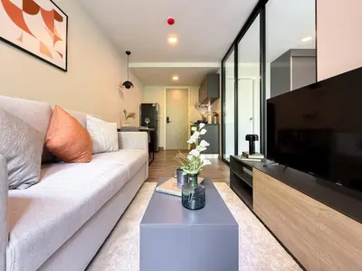 a living room with a couch and a flat screen tv at Serene Tropical 1BR - Ultra Fast Wifi - Sathorn in Bangkok