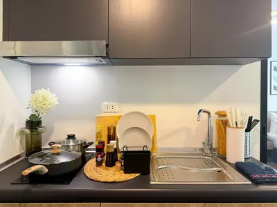 a kitchen counter with a sink and a stove at Serene Tropical 1BR - Ultra Fast Wifi - Sathorn in Bangkok