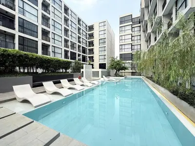 a swimming pool with white chairs and some buildings at Serene Tropical 1BR - Ultra Fast Wifi - Sathorn in Bangkok