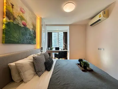 a bedroom with a bed with a painting on the wall at Contemporary Premier 1BR - Ultra Fast Wifi - BTS Nana in Bangkok