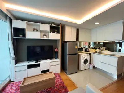 a kitchen with white cabinets and a tv in a room at Contemporary Premier 1BR - Ultra Fast Wifi - BTS Nana in Bangkok