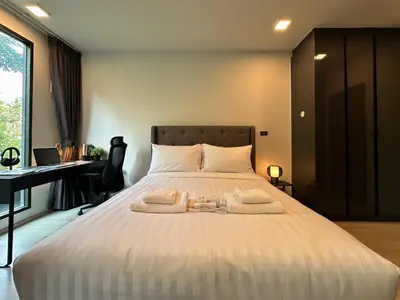 a bedroom with a large white bed with a desk at Contemporary Downtown - Ultra Fast WiFi - BTS Asoke in Bangkok