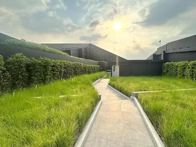 a building with a field of grass next to a building at Refined High-Rise 1BR - Fast Wifi - BTS Phra Khanong in Bangkok