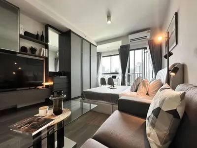 a living room with a couch and a tv at Refined High-Rise 1BR - Fast Wifi - BTS Phra Khanong in Bangkok