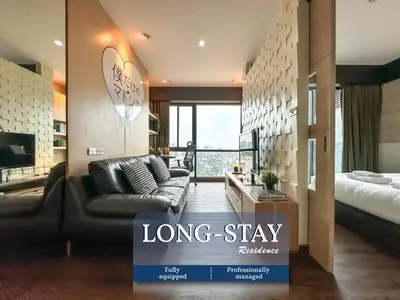 a long stay room with a couch and a bed at Transquil Modern 1BR - Ultra Fast WiFi - BTS Ari in Bangkok