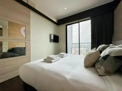 a bedroom with a large white bed with a window at Transquil Modern 1BR - Ultra Fast WiFi - BTS Ari in Bangkok