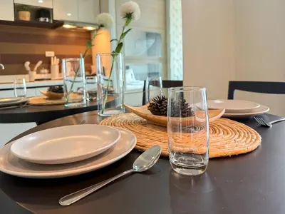 a table with plates and glasses on a table at Transquil Modern 1BR - Ultra Fast WiFi - BTS Ari in Bangkok