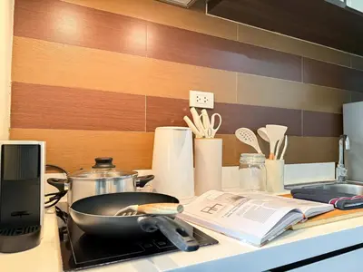 a kitchen counter with a frying pan and a book at Transquil Modern 1BR - Ultra Fast WiFi - BTS Ari in Bangkok
