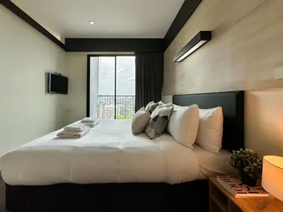 a bedroom with a large white bed with a window at Transquil Modern 1BR - Ultra Fast WiFi - BTS Ari in Bangkok