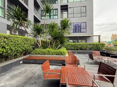 a patio with chairs and tables on a building at Transquil Modern 1BR - Ultra Fast WiFi - BTS Ari in Bangkok