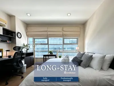 a long stay room with a bed and a desk at Centralized High-Rise - Ultra Fast Wifi - Ratchathewi in Bangkok