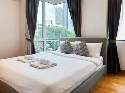 a bed with two towels on it with a window at Expansive Premier 1BR - Ultra Fast Wifi - Phrom Phong in Bangkok