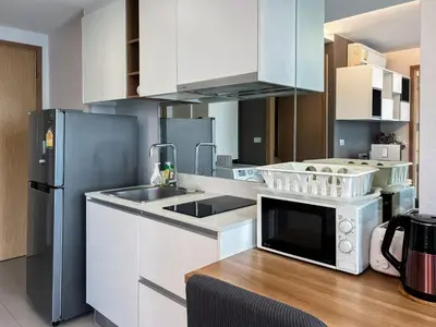 a kitchen with white cabinets and a stainless steel refrigerator at Expansive Premier 1BR - Ultra Fast Wifi - Phrom Phong in Bangkok