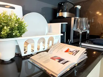 a kitchen counter with a book and a wine glass at Modern Expansive - Ultra Fast WiFi - BTS Phrom Phong in Bangkok
