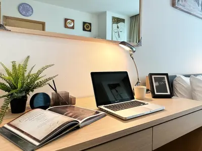 a laptop computer sitting on a desk with a book at Modern Expansive - Ultra Fast WiFi - BTS Phrom Phong in Bangkok