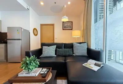 a living room with a black leather couch at Modern Expansive - Ultra Fast WiFi - BTS Phrom Phong in Bangkok