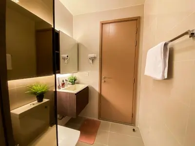 a bathroom with a toilet and a sink and a mirror at Cityscape Modern Apt - Ultra Fast Wifi - Phra Khanong in Bangkok