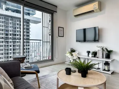 a living room with a couch and a table and a large window at Contemporary High-Rise 2BR - Ultra Fast Wifi - Sathorn in Bangkok