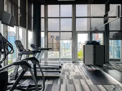 a large room with a gym with large windows at Contemporary High-Rise 2BR - Ultra Fast Wifi - Sathorn in Bangkok