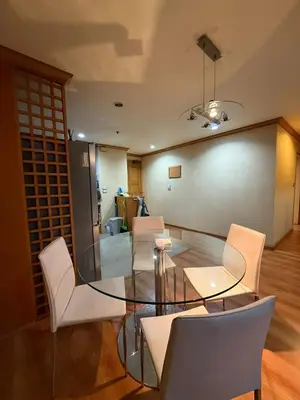 a dining room with a glass table and white chairs at Royal Place Apartments in Bangkok