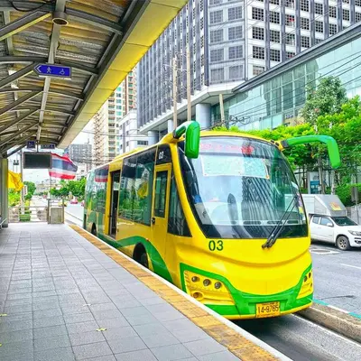 a yellow and green bus parked at a bus stop at City Living in Bangkok