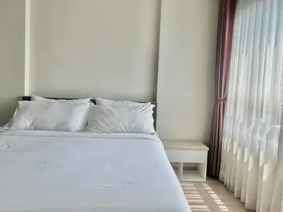 a bed with white sheets and pillows next to a window at Gfeel X Elio Sukhumvit64 in Bangkok