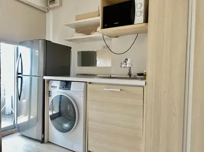 a kitchen with a washing machine and a microwave at Gfeel X Elio Sukhumvit64 in Bangkok