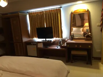 a bedroom with a desk with a computer and a mirror at Kim Hotel At Morleng in Bangkok