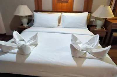 a white bed with two white flowers on it at Kim Hotel At Morleng in Bangkok