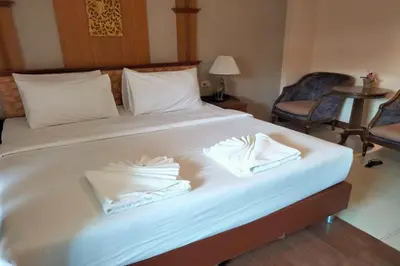 a large white bed with two folded towels on it at Kim Hotel At Morleng in Bangkok