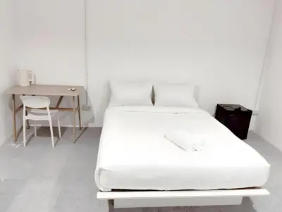 a white bed in a room with a table and a chair at XX Mitr INN Sukhumvit 2 - BTS Nana in Bangkok