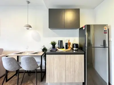 a kitchen with a refrigerator and a table with chairs at Serene Tropical 1BR - Ultra Fast Wifi - Sathorn in Bangkok