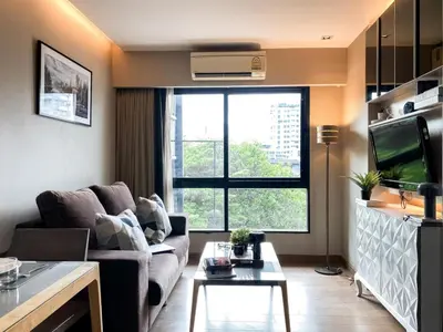 a living room with a couch and a large window at Tropical Urban 43 Sqm - Ultra Fast Wifi - Thong Lo in Bangkok