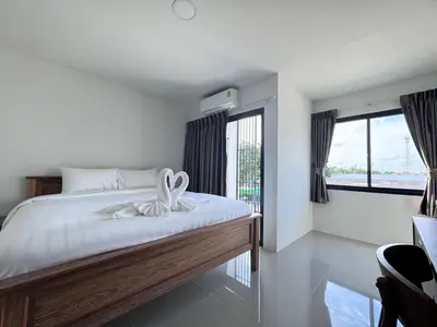 a bedroom with a bed with white sheets and windows at VS Place in Nonthaburi