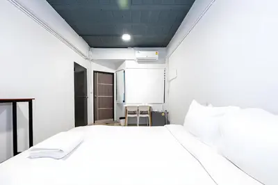 a bedroom with a white bed and a chair at Yellow Place Sukhumvit Soi 2 -เยลโล เพลส สุขุมวิทซอย 2 in Bang Kapi