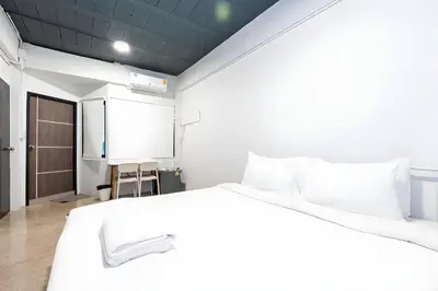 a bedroom with a large white bed and a door at Yellow Place Sukhumvit Soi 2 -เยลโล เพลส สุขุมวิทซอย 2 in Bang Kapi