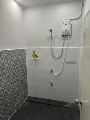 a bathroom with a shower with a hose on the wall at Cat in the box homestay in Godown