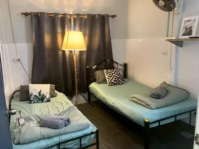 two beds in a room with a lamp and curtains at Cat in the box homestay in Godown