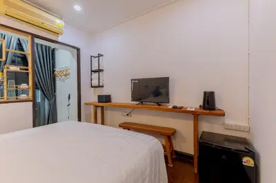 a bedroom with a bed and a desk with a television at Calmly Stay Ratchada in Bangkok